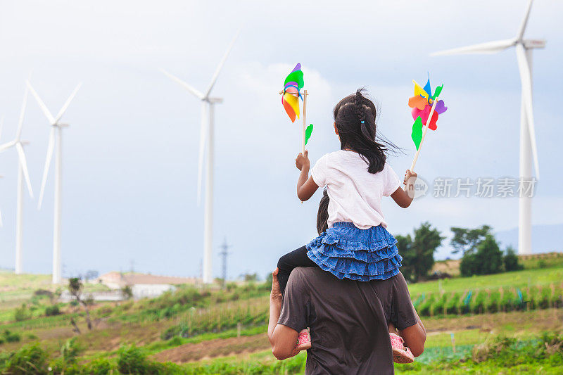 亚洲儿童女孩玩风力涡轮机和骑在父亲的肩膀在风力涡轮机领域