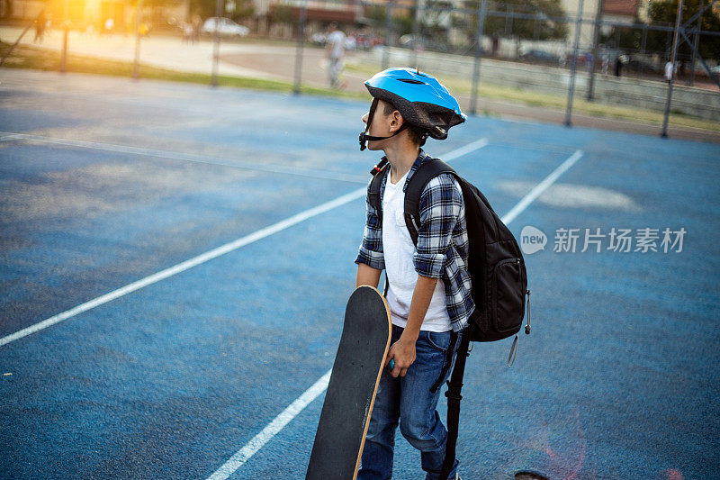 小学男孩在操场上玩滑板