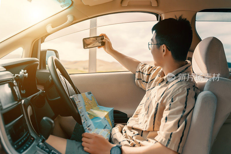 年轻的亚洲人在路上旅行，用手机拍照
