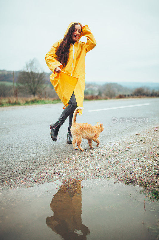 快乐的女孩和猫在大自然的雨