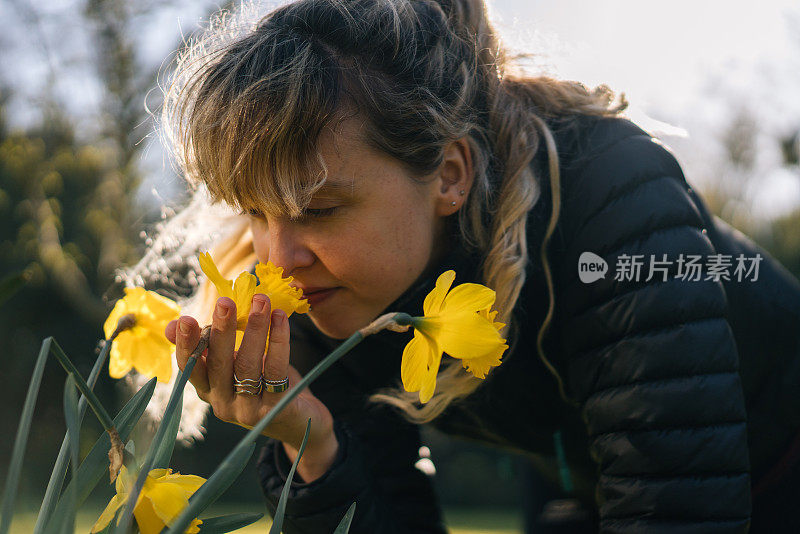 年轻女子俯身闻花香