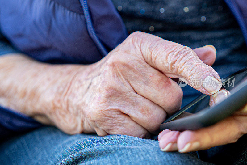 特写镜头的一个老年人的白种人的手使用智能手机的触摸屏户外