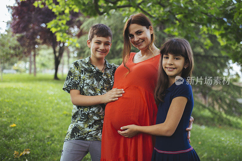 一个快乐的孕妇花时间和她的孩子们在一起，她将迎来第三个孩子。