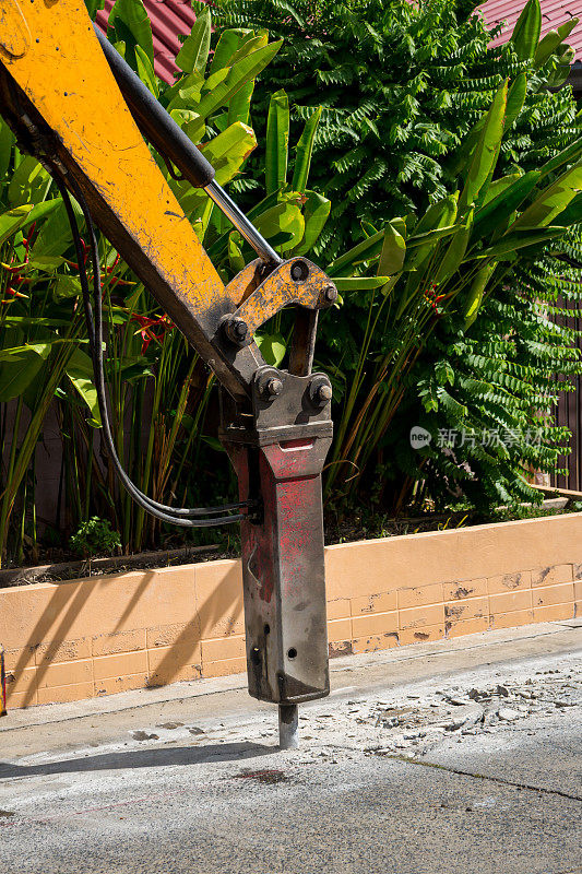 挖掘机破碎钻孔修补混凝土路面。安装在施工设备液压臂上的大型气动锤。施工车辆修路。手提钻钻