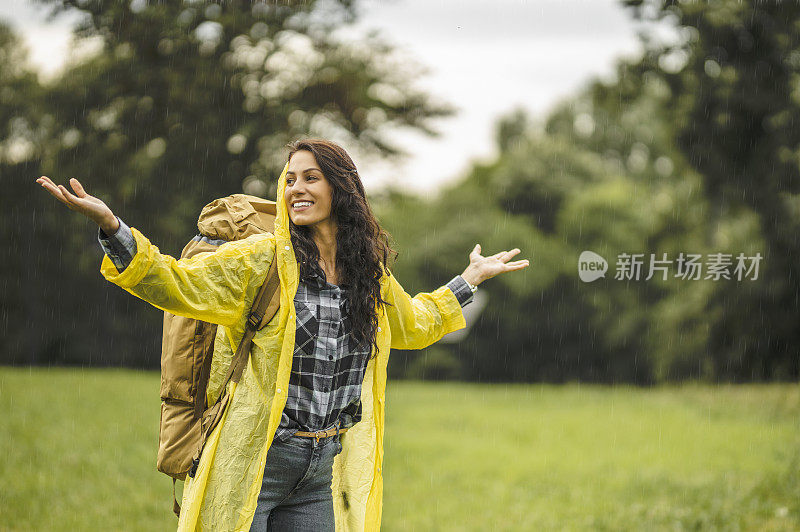 年轻女子穿着防水夹克在雨中徒步旅行