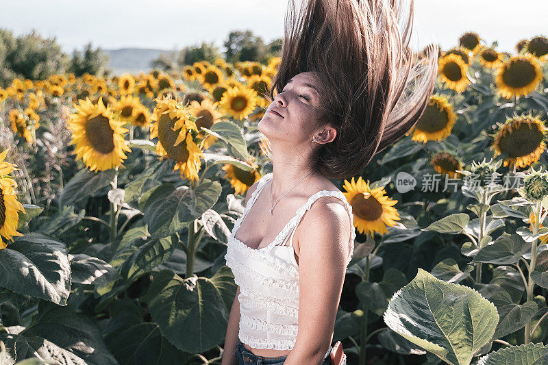 青少年的精神。动态模糊的肖像，一个年轻的少女在向日葵植物在夏天的中间。旅行和享受。生态旅游。