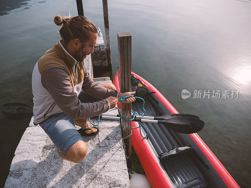 日出时分，年轻人整理独木舟到湖边码头