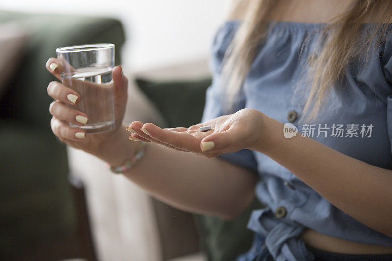 年轻女子拿着药和一杯水