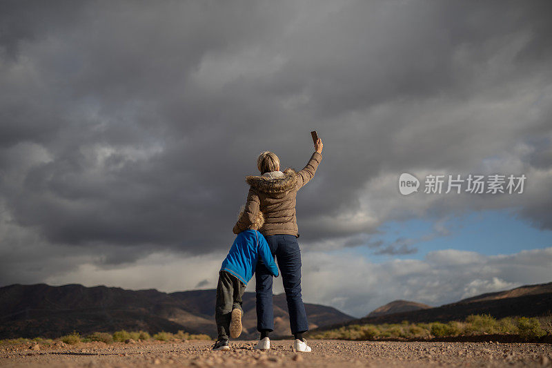 一位母亲和她的儿子正在乡间的砾石路上寻找手机信号。