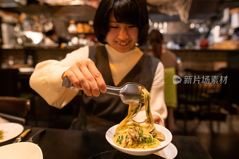 年轻女子把意大利面盛到小盘子里