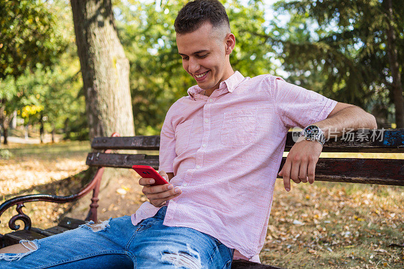 一名男子在公园长凳上玩手机