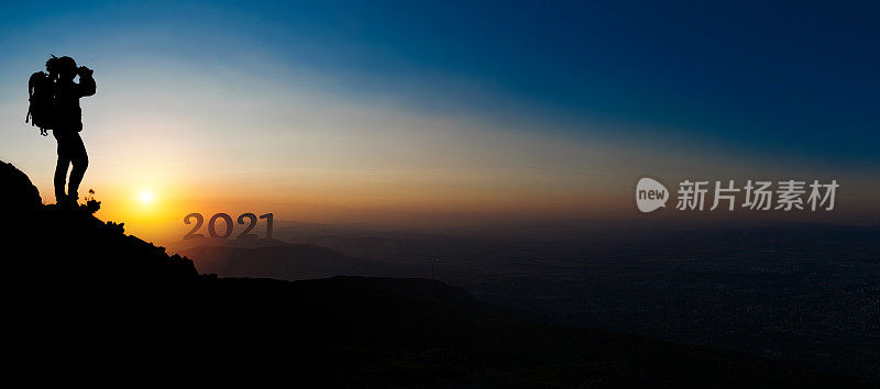 一个人爬上山顶，用双筒望远镜望着新年