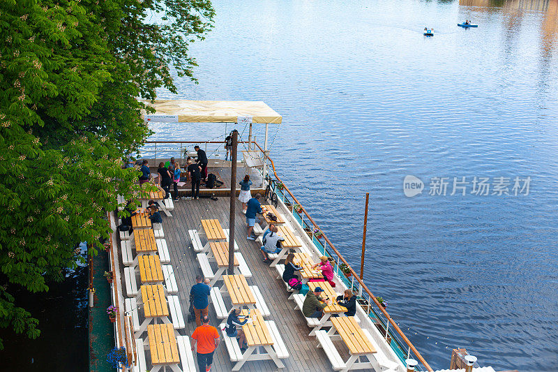 码头的顶视图，有成排的桌子供等候和休息。人们在水边休息