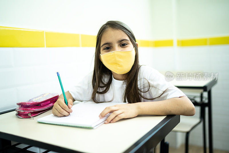 一个女学生在教室里用面具学习的肖像