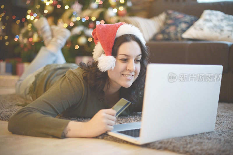年轻女子在圣诞室内，手提电脑(电子商务)