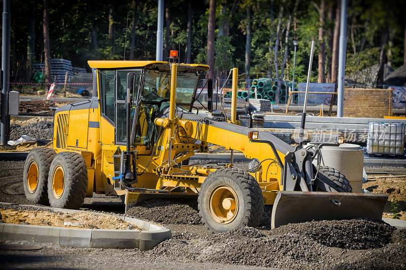 平地机将新公路施工现场的碎石弄平