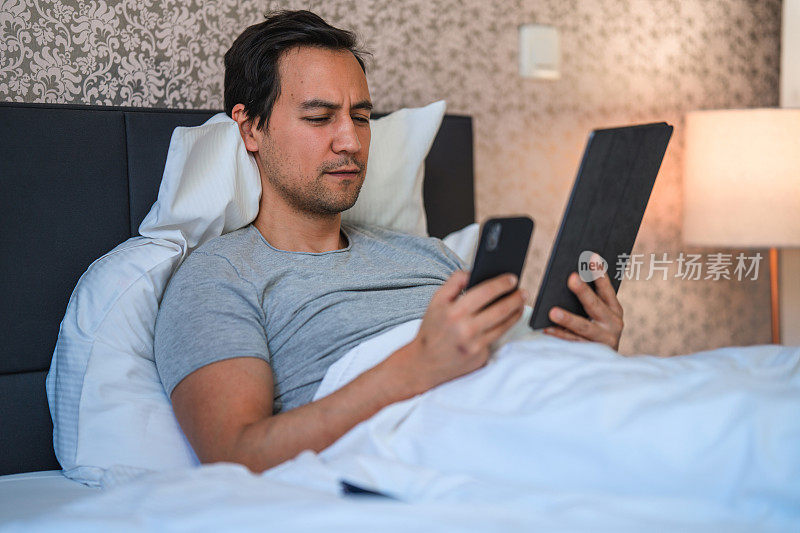 日本中年男性在卧室里使用数字平板电脑和网上购物
