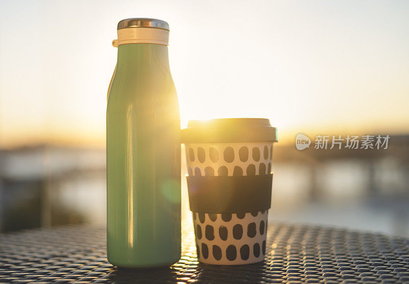 金属可重复使用的水瓶和竹可重复使用的杯子在阳光下。