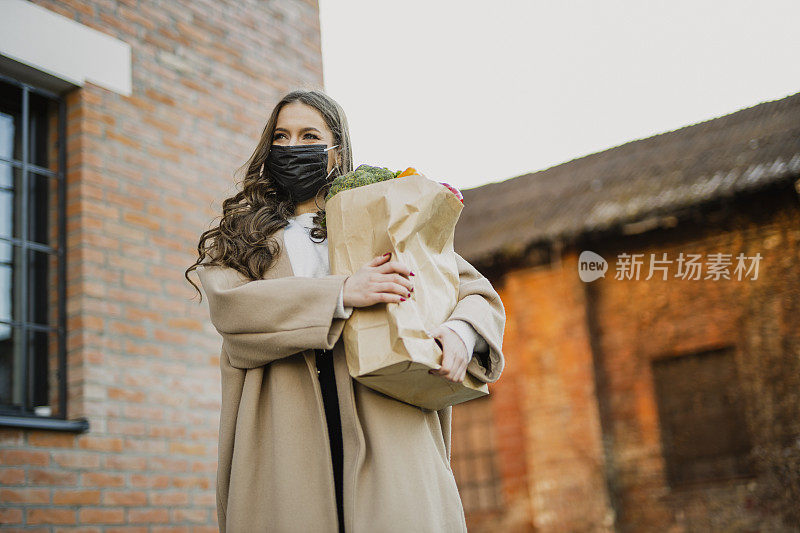 新冠肺炎大流行期间，一名年轻女子戴着防护口罩上街购物