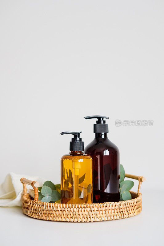 液体肥皂分配瓶与桉树和毛巾在藤托盘。SPA天然有机美容系列产品。