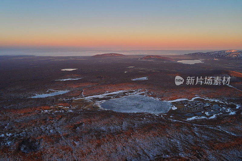 用无人机拍摄的春天日落时远处的白雪皑皑的湖泊和太平洋