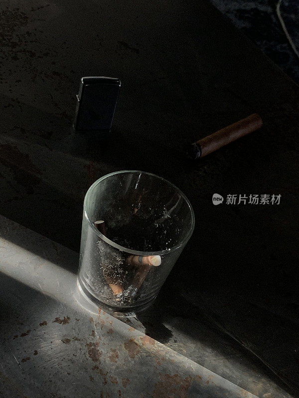 一张桌子上的一个烟鬼和一个酒鬼，一个烟头，一个雪茄和一个打火机。