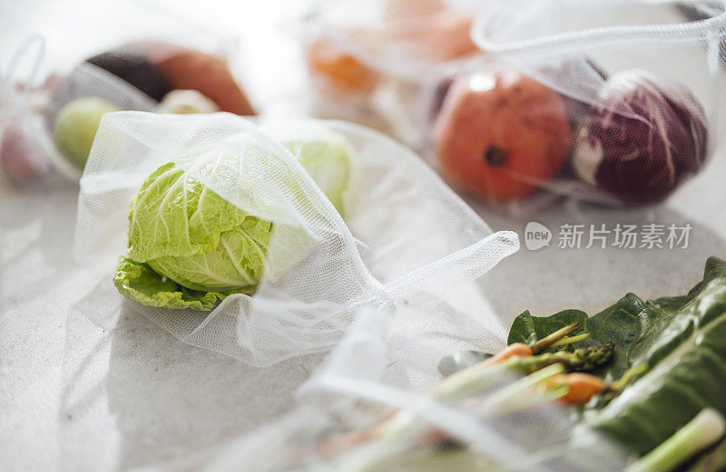 五颜六色的蔬菜和水果在网袋在厨房桌上