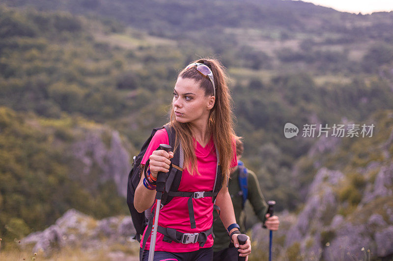 年轻的男女夫妇带着专业的装备和登山杆在美丽的大自然中徒步旅行