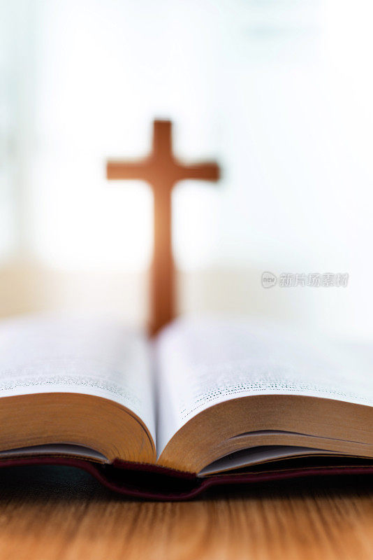 木桌上放着圣经和宗教十字架
