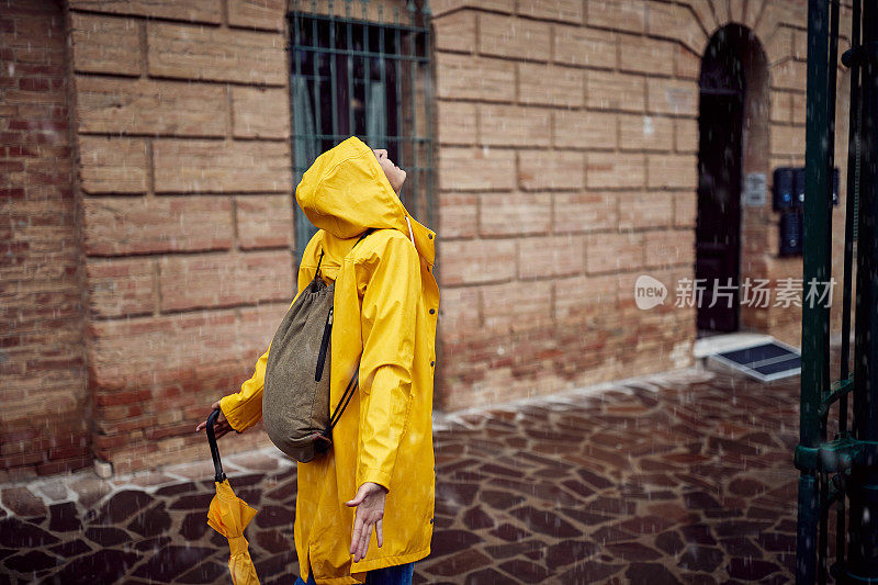 一个年轻的女孩喜欢下雨天在城市里散步时感觉雨点落在她身上。走,雨,城市