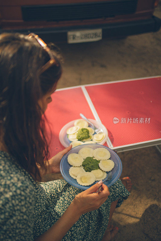 年轻女子在户外吃新鲜的意大利饺子和香蒜沙司