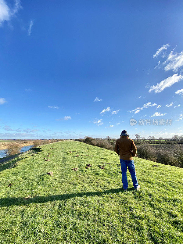 男子在标志性的林肯郡平原沼泽景观与排水堤坝