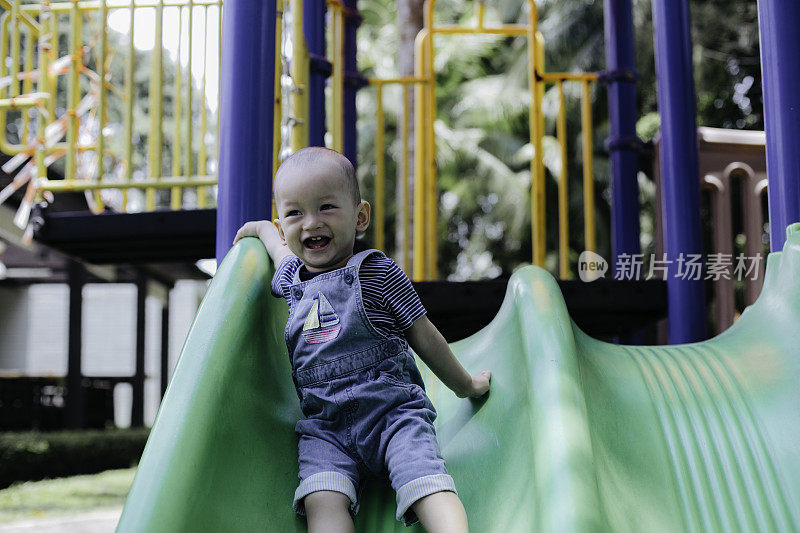 一个小男孩在操场上玩滑梯