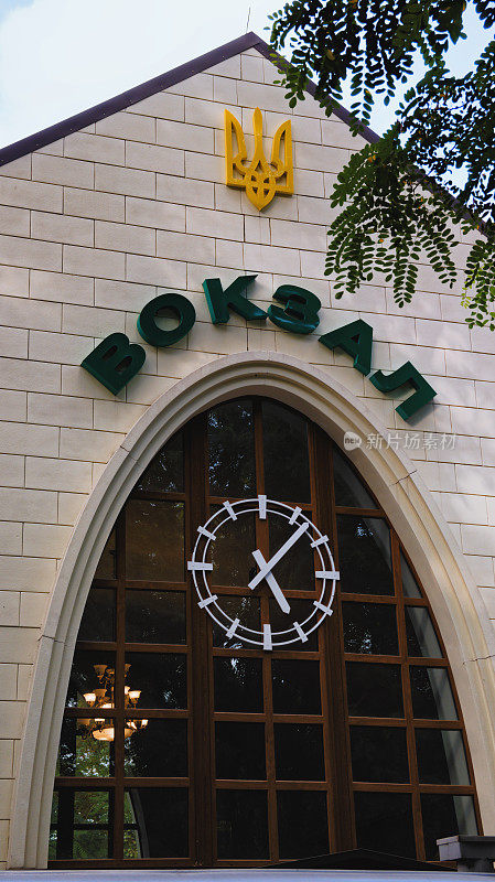 火车站正面的上部有乌克兰语的Vokzal(英语:station)和现代时钟。高角度的观点。树叶边界。Syretsky公园的基辅儿童铁路