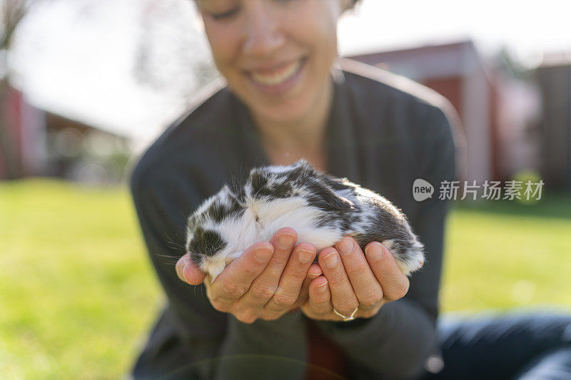 一名妇女在农场外面抱着宠物小兔子