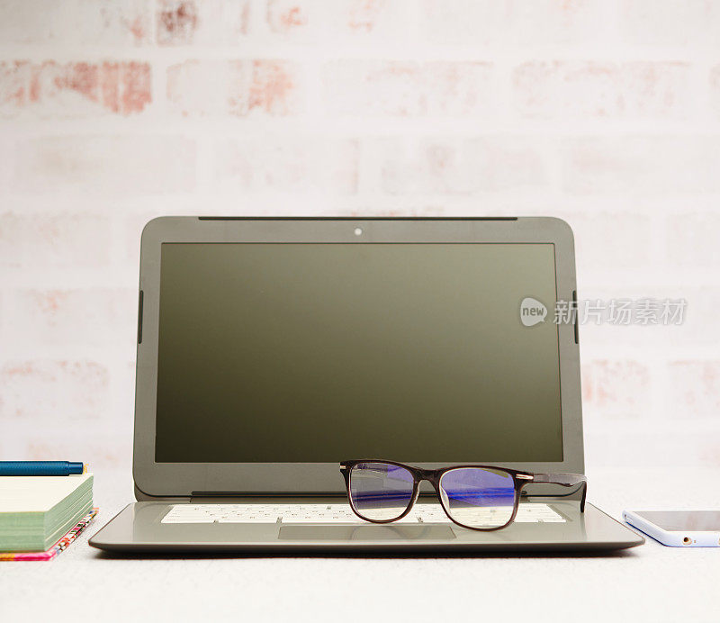 商务静物与笔记本电脑在明亮的办公室设置。键盘上的眼镜