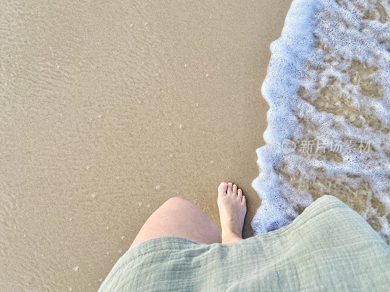 赤脚走在沙滩上的沙子和水