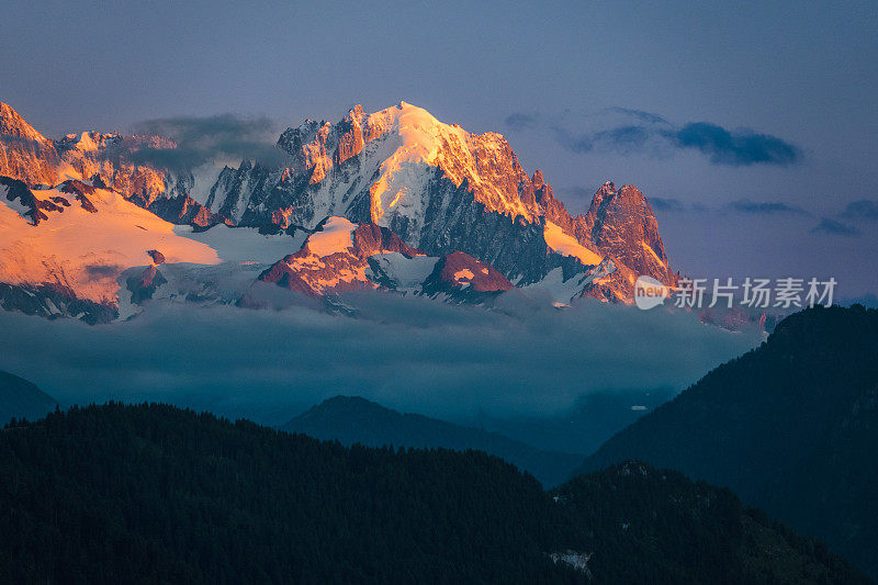 日落时美丽的山景，将岩石和雪变成橙色