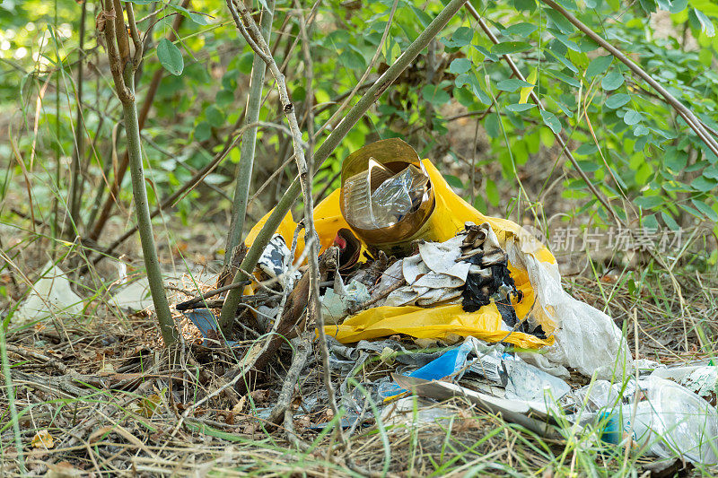 森林里的垃圾堆散落在草地上。野餐后树林里的塑料垃圾。