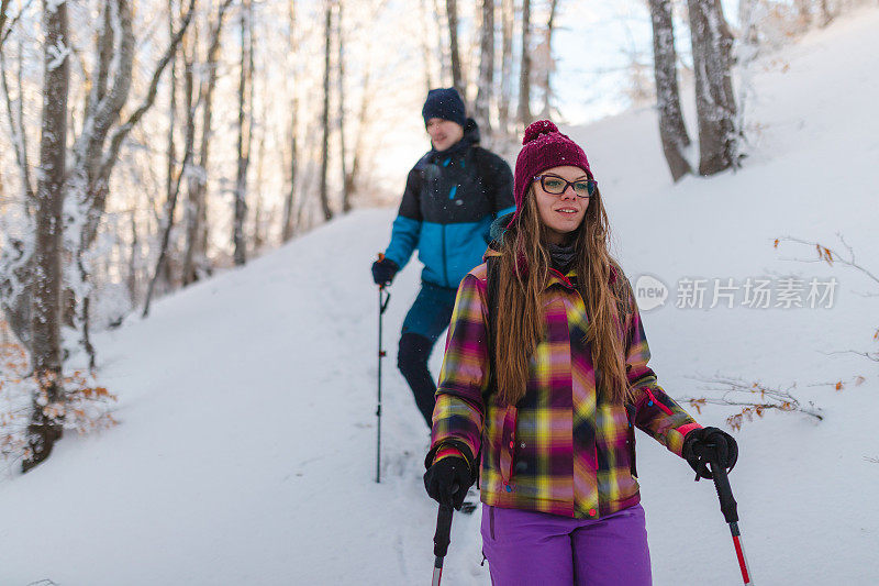 美丽的年轻女子徒步旅行一起与她的男性朋友在雪山