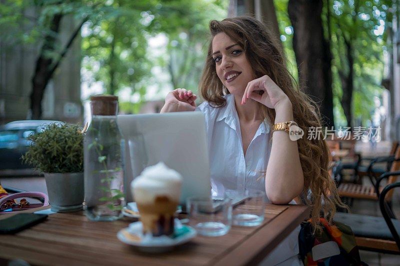 女商人使用笔记本电脑，同时享受工作在咖啡桌上一杯咖啡