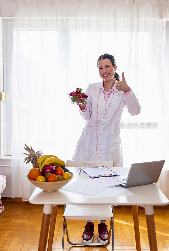 年轻的女性营养学家拿着一碗新鲜的草莓