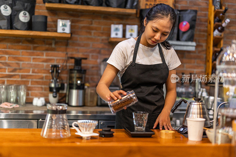 一位微笑的印尼年轻女子在咖啡馆用传统的方式准备咖啡