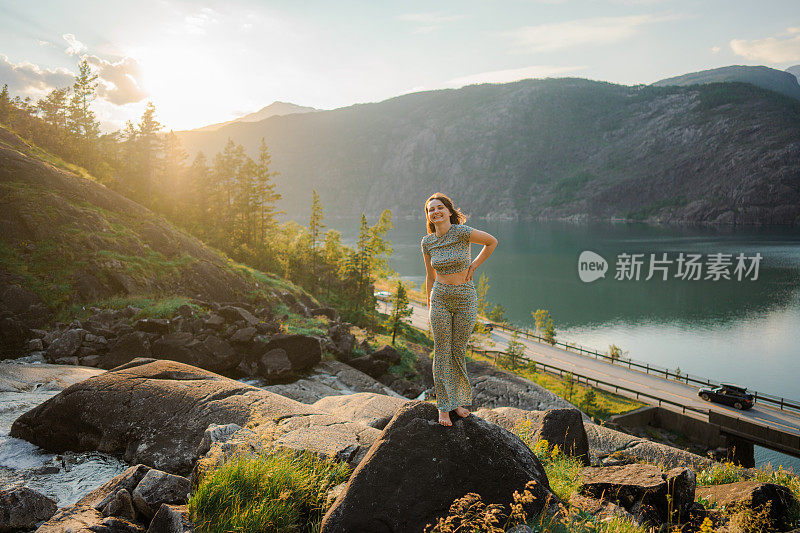 一名女子站在挪威的瀑布旁，看着峡湾