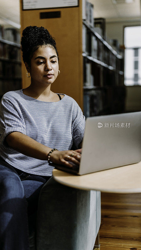 20多岁的多种族女性在图书馆或书店里使用笔记本电脑