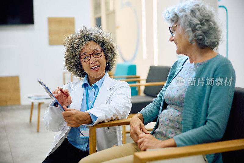 女医生和高级妇女在诊所候诊室谈论医疗文件。