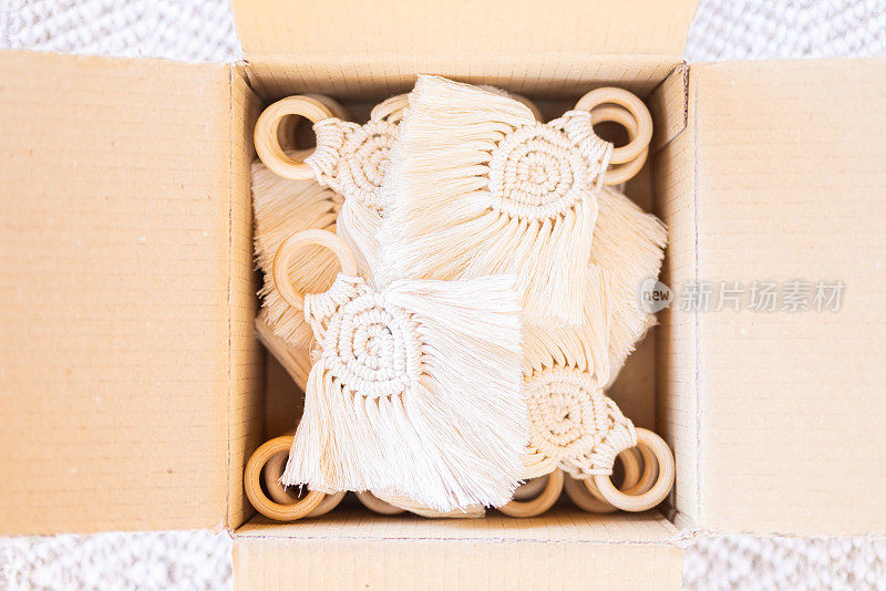 优雅的米色编织餐巾架上有手工制作的图案和木环，精心包装在纸板箱里，以展示其复杂的设计和工艺