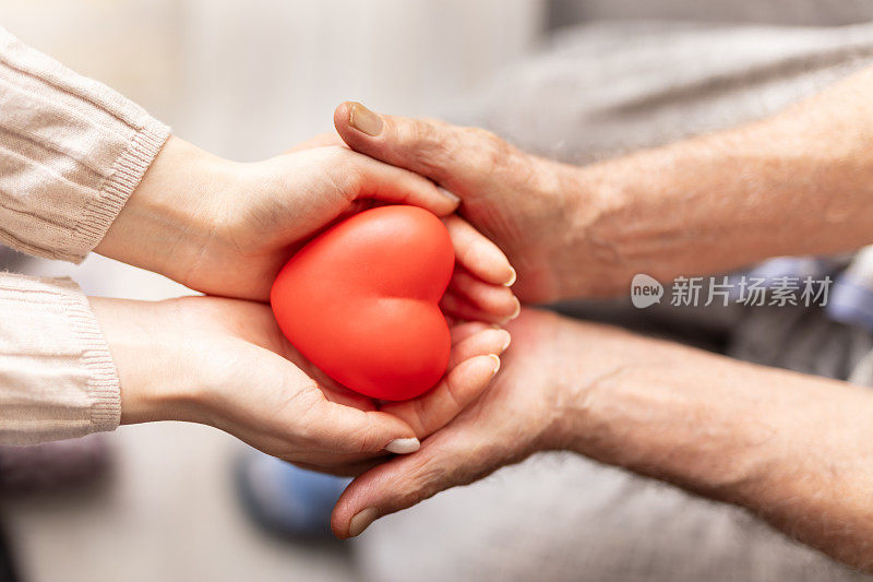 老人或爷爷奶奶用红心的双手扶持护理