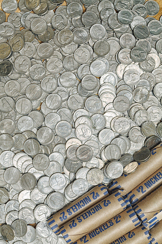 美国镍币包裹在2美元的纸卷和散落的硬币中