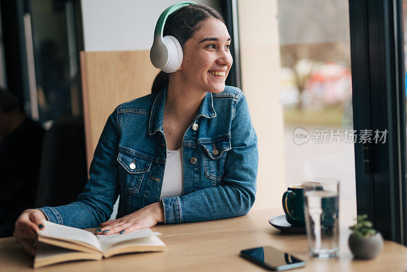 一个年轻女子一边听音乐一边看书的照片